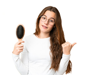 Teenager girl with hair comb over isolated chroma key background pointing to the side to present a product