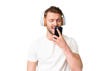 Young handsome caucasian man over isolated chroma key background listening music with a mobile and singing