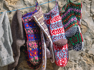 Woolen knitted socks for the cold season. Socks made of natural wool, knitted. Handmade products. Multicolored knitted socks on the background of a stone wall.