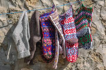 Woolen knitted socks for the cold season. Socks made of natural wool, knitted. Handmade products. Multicolored knitted socks on the background of a stone wall.