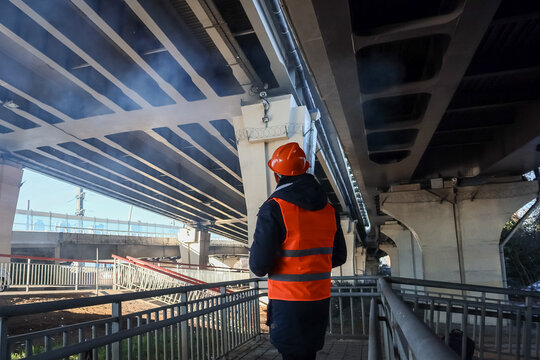 Back view of worker inspecting urban bridge base