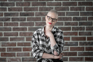 Portrait of a beautiful young caucasian woman with shaved head. Female cancer survivor. Smiling Woman with Glasses Posing Confidently in a Studio Environment. Model Has Glaucoma. Waering Plaid Shirt