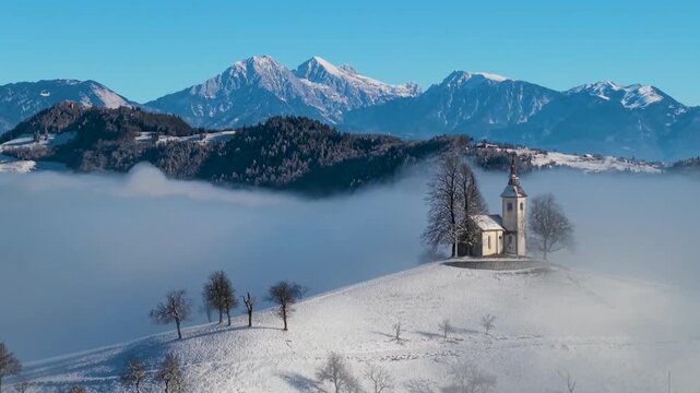 Breathtaking Winter scenery - iconic Jamnik church and village in Fog: Epic Aerial drone footage at Sunrise. 4k