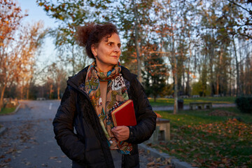 Thoughtful woman with book in park