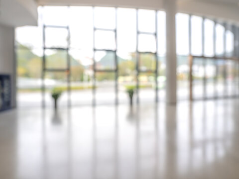 Blurred background of modern glass building with natural light symbolizes eco-friendly architecture, green business, sustainability, and clean energy design in urban lifestyle and office space.