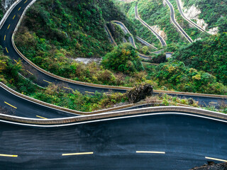 Winding mountain road at Tianmen in China with sharp curves and lush green scenery. Known as 99 Bends, this thrilling highway offers dramatic views and epic travel adventure.