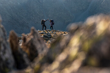 Hiking partners celebrating summit above dramatic mountain walls