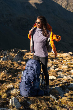 Female hiker slipping into protective jacket under calm mountain light