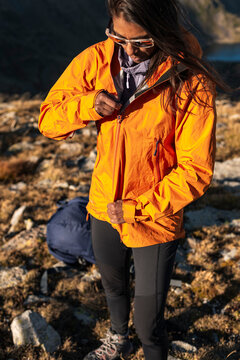 Focused hiker adjusting technical jacket with unhurried precision