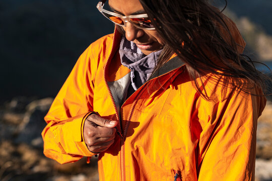 Outdoor female hiker closing jacket against cool alpine breeze
