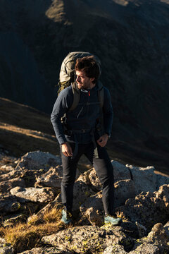 Calmly protected male hiker pausing confidently on rugged mountain terrain
