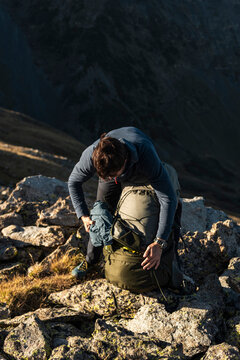 Grounded hiker accessing insulated jacket for thermal balance in altitude