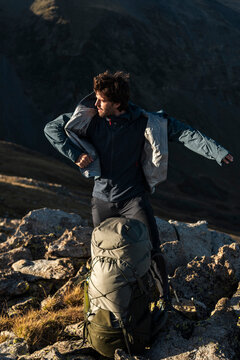 Hiker donning technical jacket for sustained mountain effort