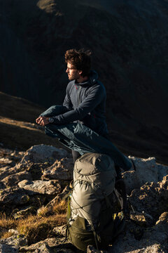 Composed trekker preparing outer layer amid quiet alpine exposure
