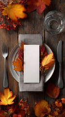 Rustic thanksgiving table setting with blank card, cutlery, and vibrant autumn foliage on wood