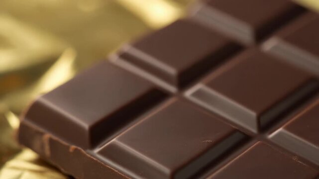 Close up of a dark chocolate bar on golden foil wrapper.