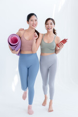 Happy Asian friends in activewear walking to a yoga class
