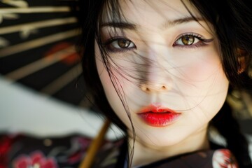 Close up portrait of beautiful young japanese woman with red lipstick holding traditional umbrella