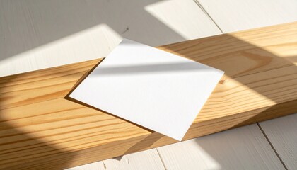 Blank white paper on a wooden plank with soft shadow overlaying the surface, a simple and clean composition