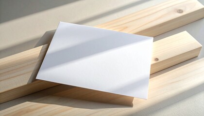 Clean blank white card template on light wooden planks, illuminated by a dappled natural sunlight shadow, perfect for rustic or minimalist design mockups and branding presentations