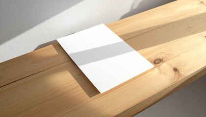 Blank paper lying on a wooden surface bathed in natural light, casting a subtle shadow