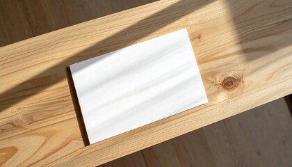 Blank white card with shadow on wooden table, top view