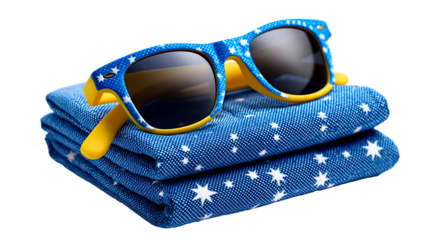 Stack of folded Australian flags beside blue sunglasses on a plain surface during daylight hours
