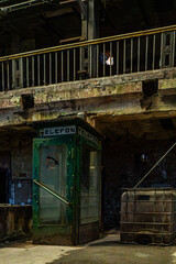 Abandoned factory floor with telephone booth and debris