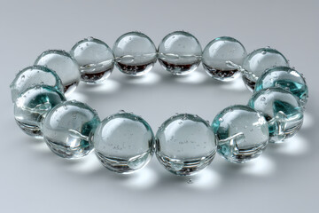 Obraz premium Glass sphere ring connected by tiny water bridges, minimalist studio setup with copy space