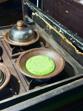 Traditional Indonesian pandan serabi cooking on clay mold using traditional stove. December 20, 2025 - Tangerang, Indonesia.