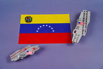 The flag of Venezuela is surrounded by American military equipment. Confrontation, conflict.