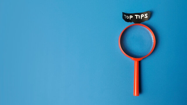 Top Tips Sign with Red Magnifying Glass on Blue Background for Expert Advice Best Practices Success Guide and Business Tutorial Concept