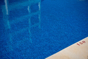 Clear pool water with reflections, showing the water level marker at 180 cm on the poolside