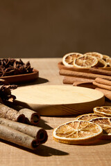 Fototapeta premium Scene of herbal tea ingredients such as cinnamon and dried citrus on wooden surface. Brown background and blank space for healthy beverage branding and editorial use