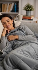 Fototapeta premium Contented young woman resting comfortably under a plush cover while relaxing indoors