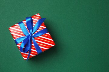 Top view of beautiful Christmas gift box with ribbon on green background