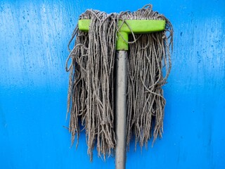 Dirty Mop Hanging on Blue Wall Background