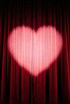 Red velvet theater curtains with a soft heart-shaped spotlight
