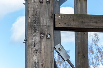 Close-up of a wooden structure with bolts and metal joints outdoors.