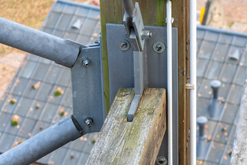 Metal fastening of diagonal pipes to a wooden beam in a supporting structure.