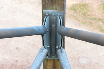 The central attachment point for diagonal metal pipes to a wooden support.
