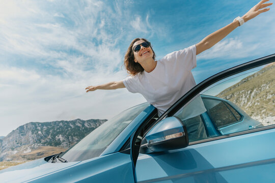 Woman with arms up having fun, car travel concept