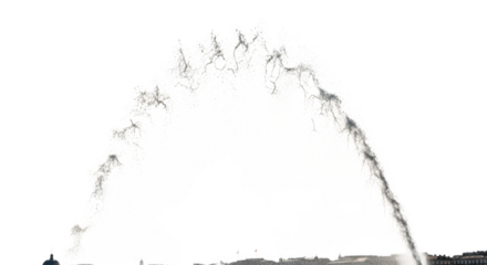 Large water jet spraying upwards against a black background with a silhouetted cityscape below fountain