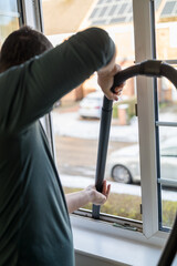 Spring home cleaning. Man vacuums plastic window frame.