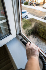 Cleaning the window. A man with steam device removes dirt from the plastic window frame.