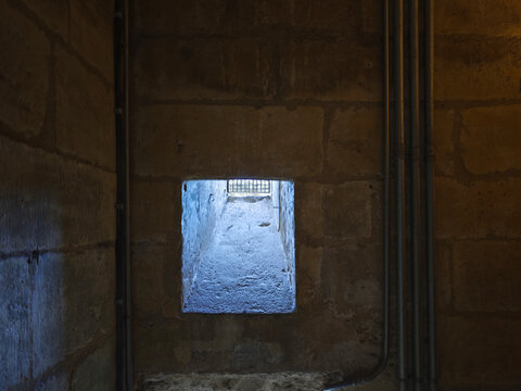 Ventana con barrotes en un grueso muro de piedra