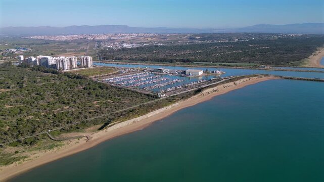 Aerial view of Guardamar del Segura, a town on the Costa Blanca in Spain. Segura River flowing to the Mediterranean Sea, marina with boats, sandy beaches and surrounding urban and natural landscapes.