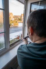 Spring home cleaning. Man vacuums plastic window frame.