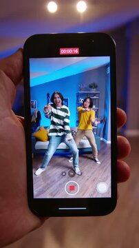 POV smartphone view capturing user generated dance content with Asian teen boys performing synchronized routine in cozy living room modern UGC creator vibe