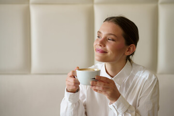 Smiling businesswoman enjoying a coffee sitting in a chic cafeteria